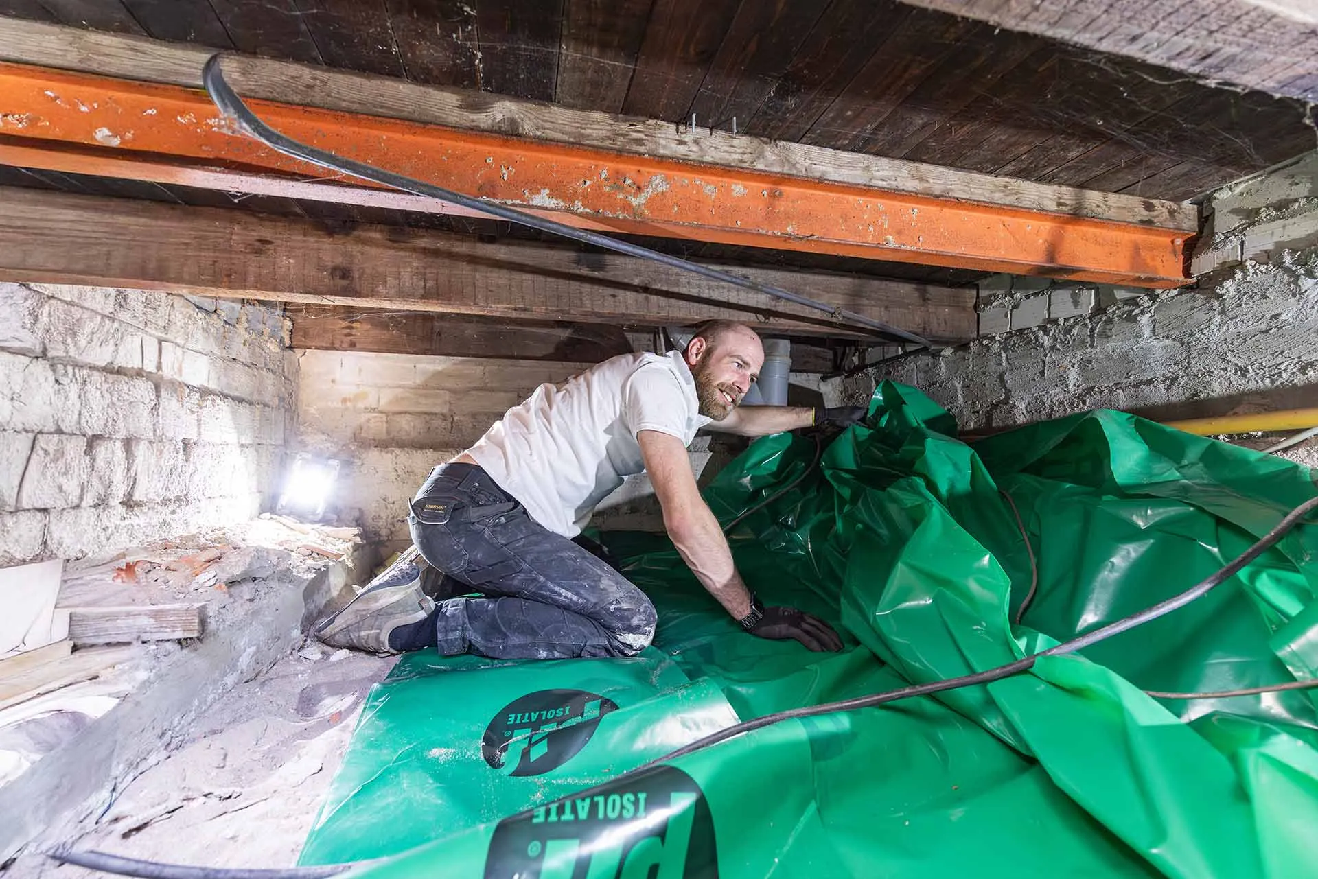Monteur legt bodemisolatie aan op de bodem van de kruipruimte in een woning in Haarlem